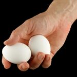 Рука держит два белы яйца